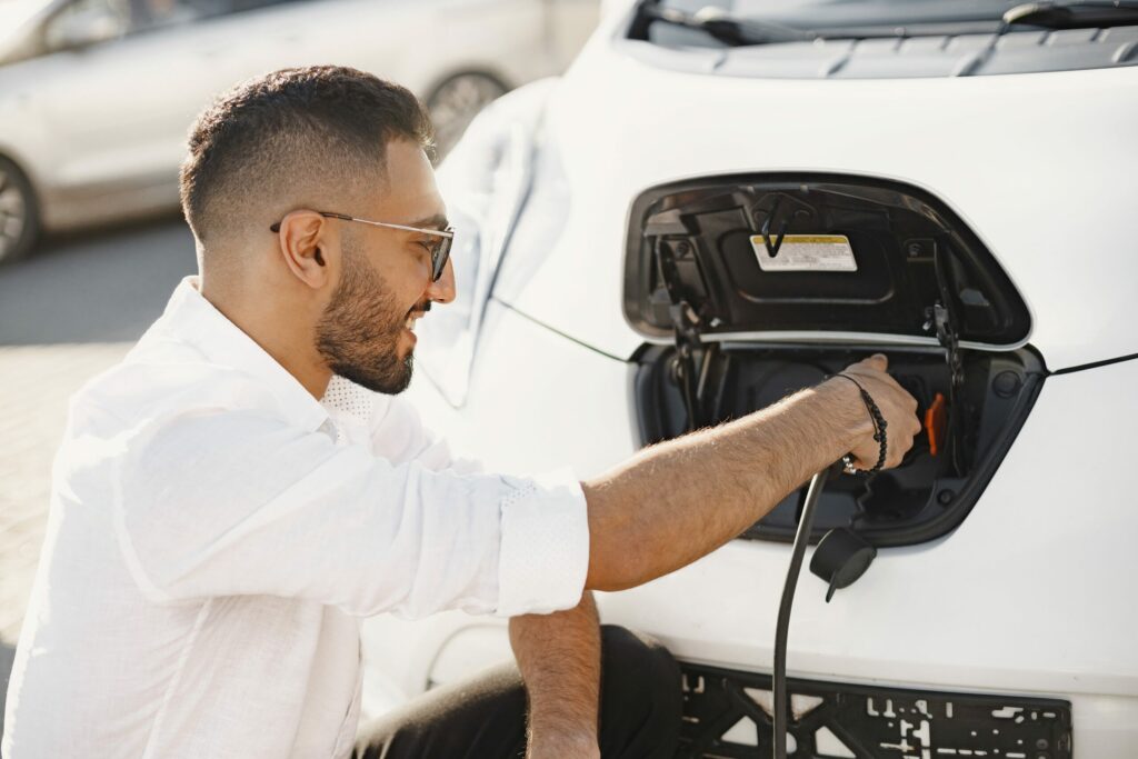 Young man charging his electric car, a symbol of sustainable urban electromobility.