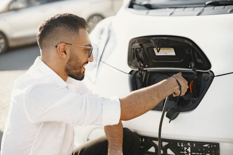 Jeune homme rechargeant sa voiture électrique, symbole de l’électromobilité urbaine et durable.