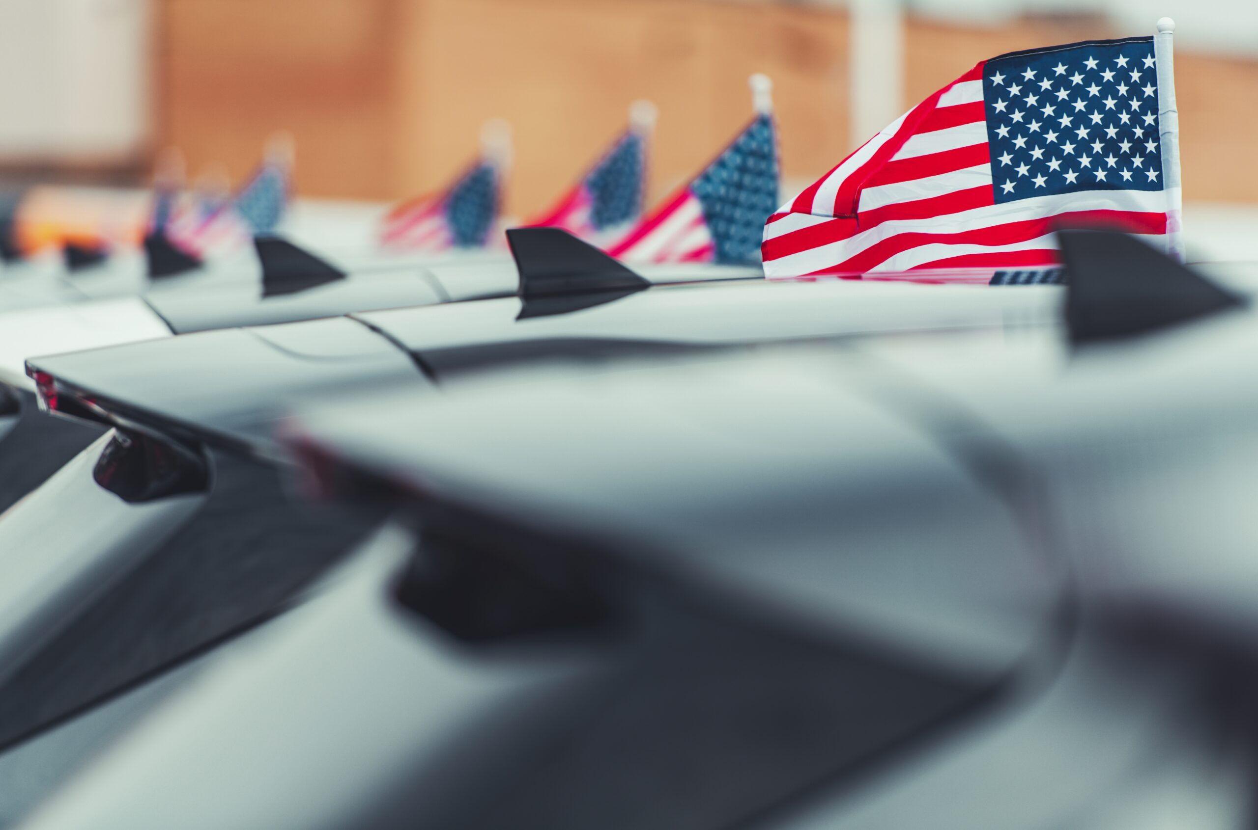 Electric vehicles parked in front of American flags, representing the US EV market.