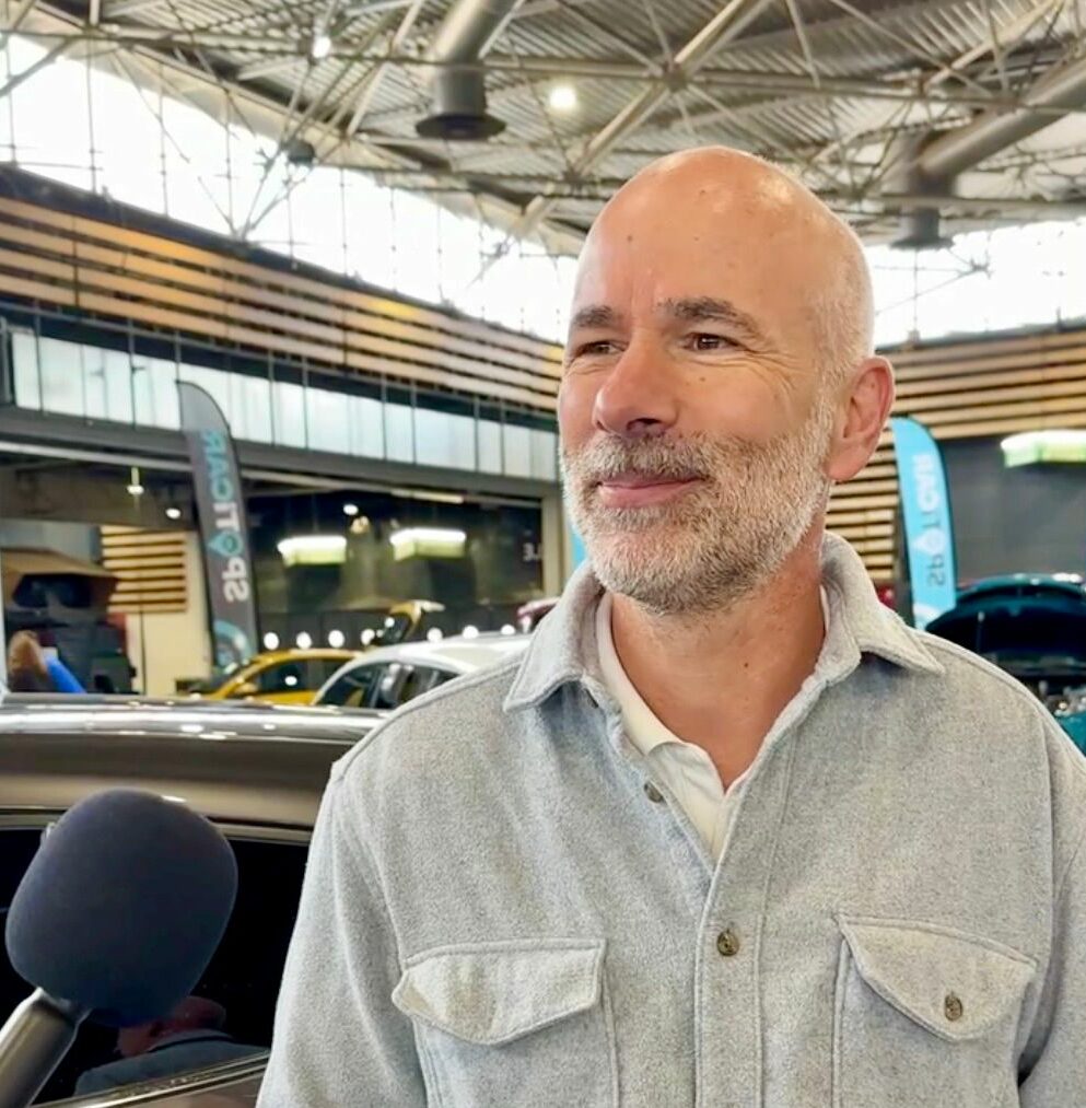 Homme interviewé au Salon de l’automobile de Lyon sur les véhicules électriques