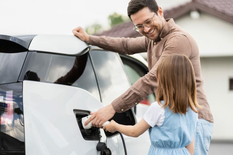 Homme et sa fille rechargent une voiture électrique à domicile