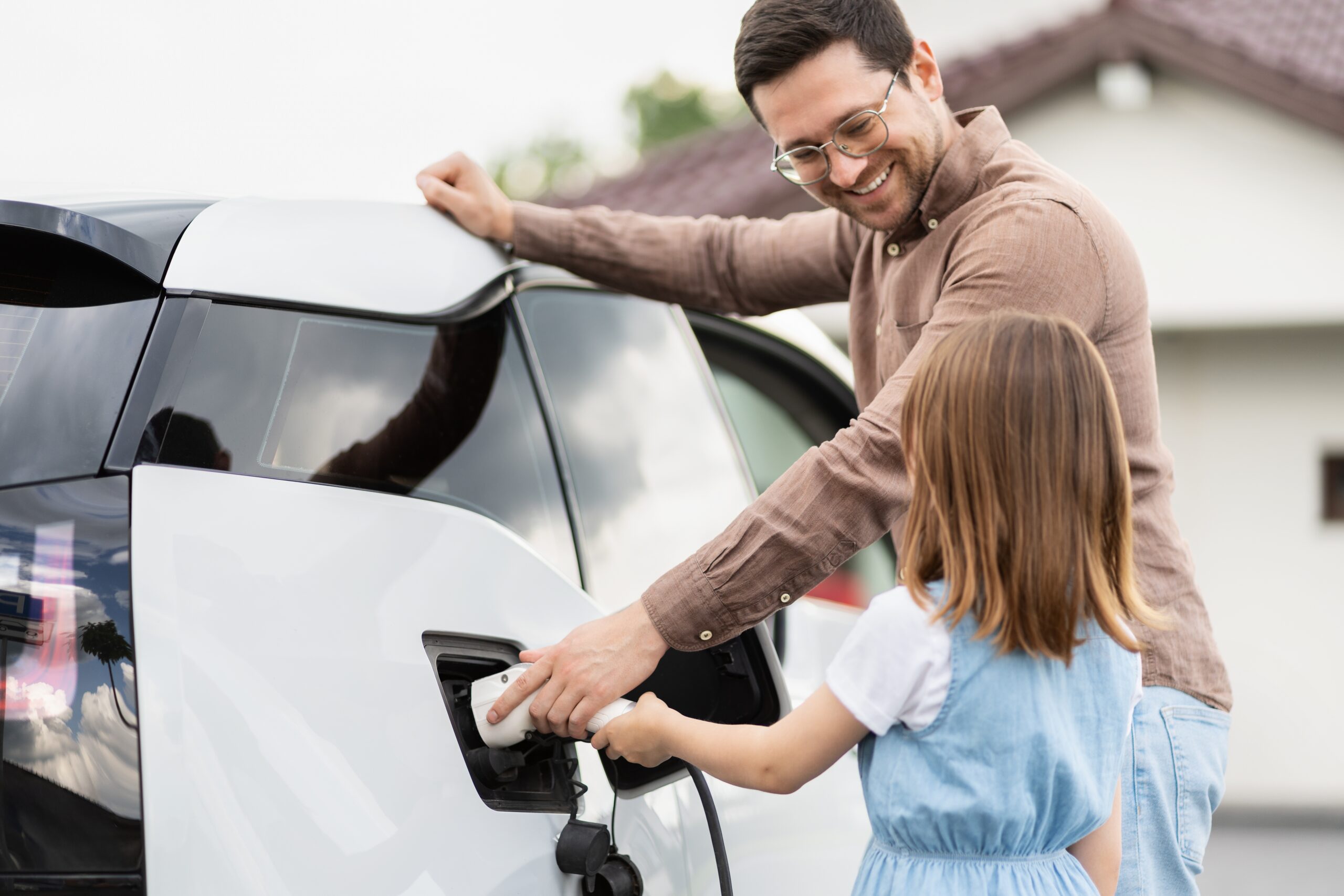 Homme et sa fille rechargent une voiture électrique à domicile