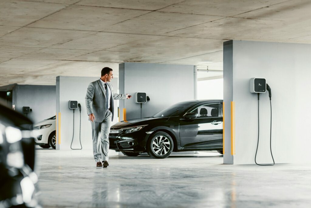 Homme quittant son véhicule électrique branché sur une borne de recharge à domicile